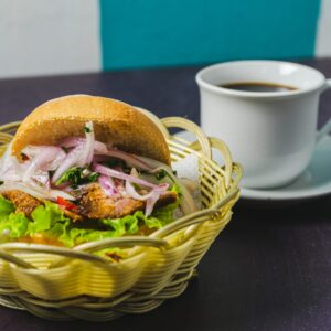 A delicious sandwich with fresh ingredients paired with a hot cup of coffee on a rustic table.