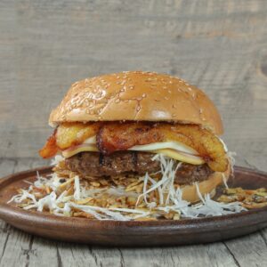 Delicious gourmet burger with plantains, cheese, and cabbage on a ceramic plate.