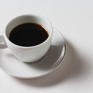 A single coffee cup with a dark brew on a bright white surface.
